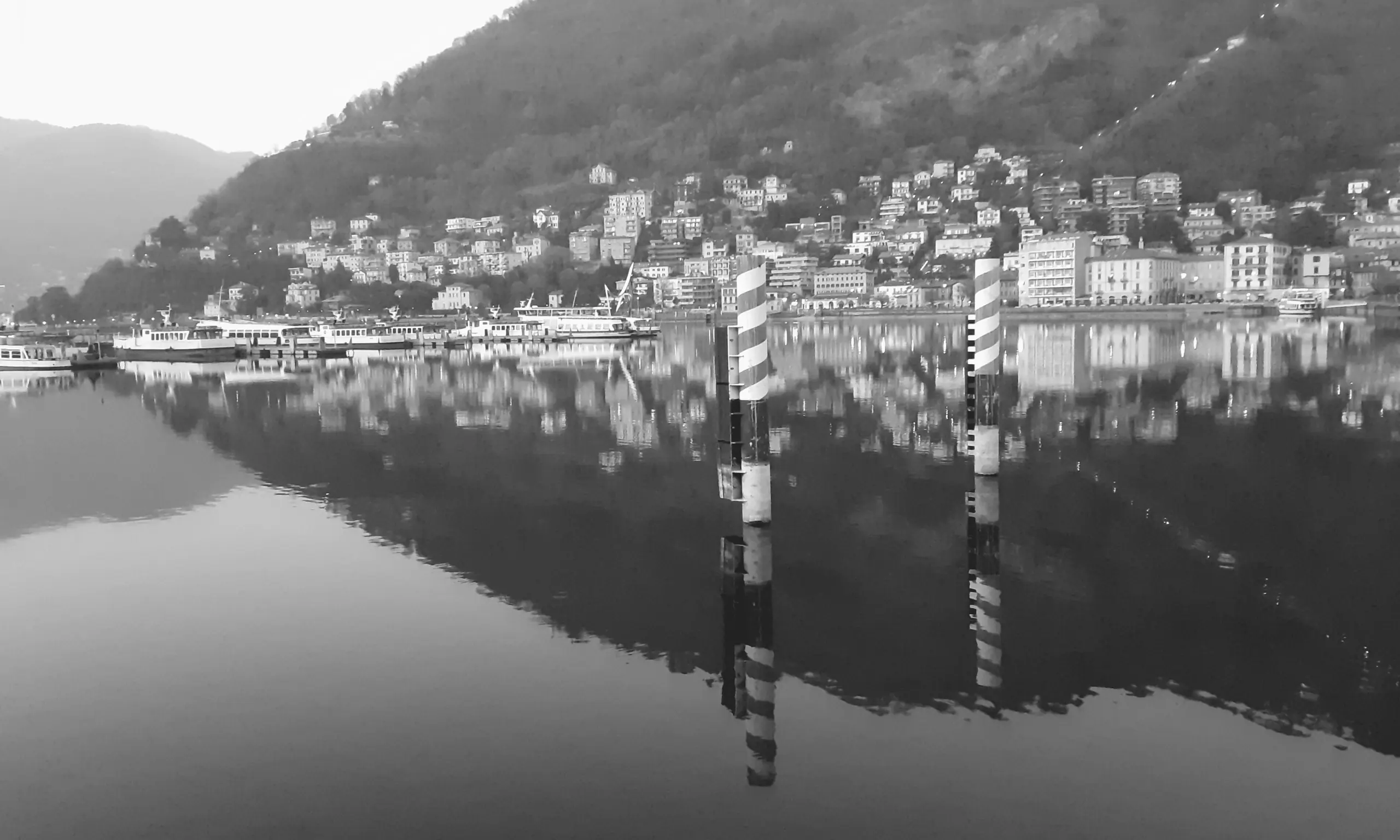 Il lago di Como fermo come uno specchio: la collina di Brunate e il suo riflesso.